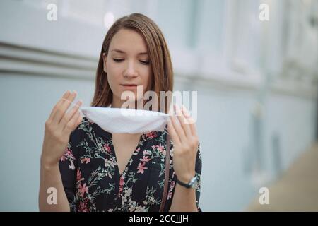 Junge Frau Porträt setzen auf Gesichtsmaske im Freien Virenschutz Stockfoto