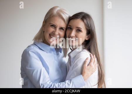 Glückliche ältere Mutter, die ihre Erwachsene Tochter herzlich umarmt Stockfoto