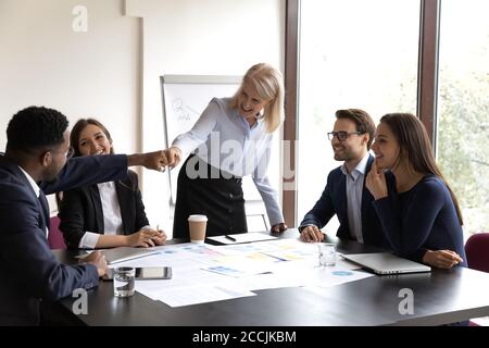 Glücklich reifen Geschäftsfrau Bumping Fäuste mit jungen afrikanischen Kollegen Stockfoto