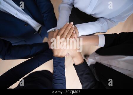 Die Mitarbeiter des Unternehmens stapeln sich bei Teambuilding-Schulungen Handflächen zusammen Stockfoto