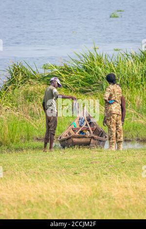 Murchison Falls National Park / Uganda - Februar 20 2020: Ein nicht identifizierter Fischer verkauft seinen Fang vom See Victoria an einen Ranger. Stockfoto