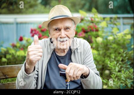 Porträt eines lächelnden und selbstbewussten Senior 87 Jahre alt niedlich in einem Hut mit Schnurrbart. Glückliches aktives Alter Stockfoto