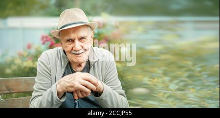 Porträt eines lächelnden und selbstbewussten Senior 87 Jahre alt niedlich in einem Hut mit Schnurrbart. Glückliches aktives Alter. Stockfoto