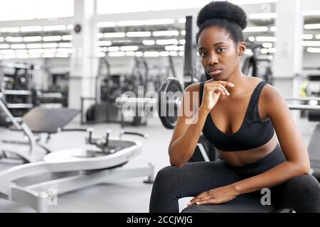 crossfit afrikanische Frau sitzt im Fitnessstudio, Ruhe, eine Pause nach dem Cross-Fit-Training mit Langhantel. Kraft, Kraft, gesunder Lebensstil, Sportkonzept Stockfoto