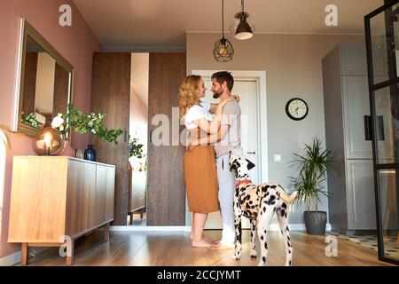 Paar tanzen langsamen Tanz, erleben Liebe zu Hause. Adorable dalmatinischen Haustier Hund Blick auf Besitzer, entspannte Zeit im Wohnzimmer Stockfoto