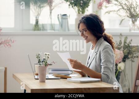 Lächelnd junge Geschäftsfrau Lesen Papier Brief Korrespondenz. Stockfoto