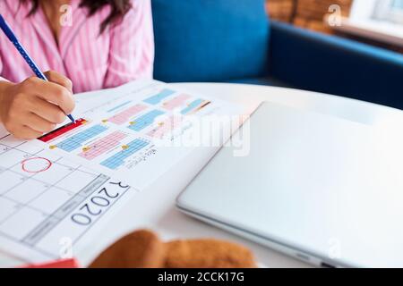 Junge hübsche zukünftige Mutter mit Kalender zu Hause und wartet ungeduldig auf ihr Baby Fälligkeit, Notizen machen Stockfoto