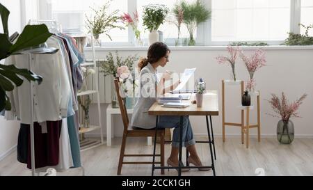 Fokussierte Millennial Mode-Designer Kaffee trinken, arbeiten mit Dokumenten. Stockfoto
