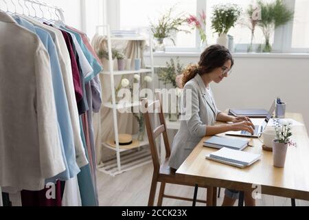 Junge glückliche Stylistin Beratung Kunden online im Showroom. Stockfoto