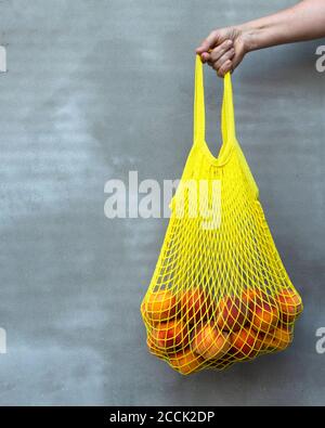 Yelow Netzbeutel oder String-Beutel mit reifen Pfirsichen in der Frau Hand. Keine Verschwendung. Stockfoto
