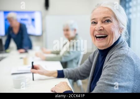 Glückliche ältere Frau, die den Schulkurs für Senioren besucht Stockfoto