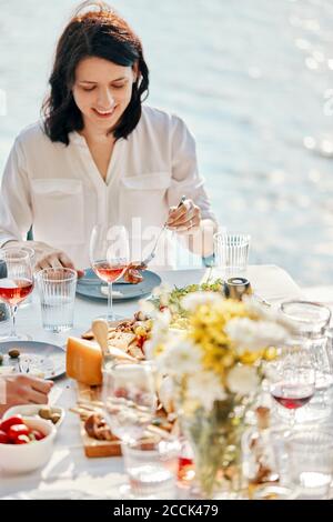 Junge Frau beim Abendessen an einem See Stockfoto