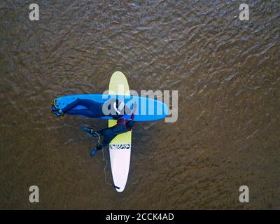 Luftaufnahme von zwei Surfern, die auf Surfbrettern in Braun liegen Wasser der Barentssee Stockfoto