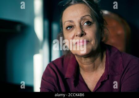 Nahaufnahme einer nachdenklichen älteren Frau, die beim Sitzen wegschaut Zu Hause Stockfoto