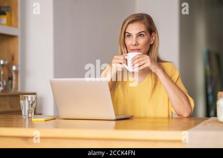 Nachdenklich reife Frau trinken Kaffee, während am Tisch sitzen Stockfoto
