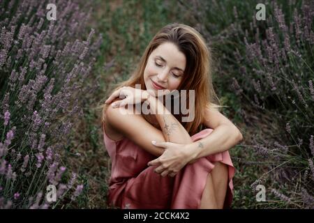 Frau, die im Lavendelfeld sitzt Stockfoto