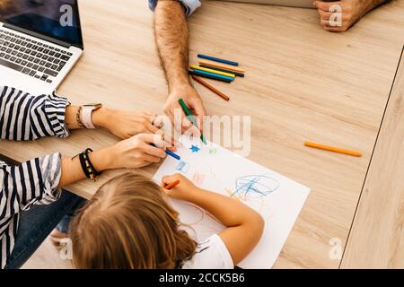 Hände von Eltern malen mit Tochter auf Papier über Essen Tisch zu Hause Stockfoto