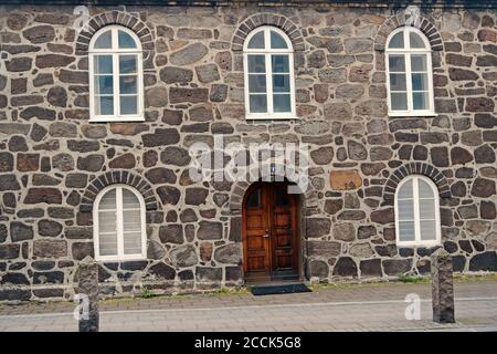 Alte steinerne Gebäude mit Windows. Wand, die aus großen Steinen. Alte Material Konzept. Alte steinerne Haus oder Teil der Verteidigungsanlagen. Gebäude mit dicken Wänden und schwere hölzerne Tür. Stockfoto