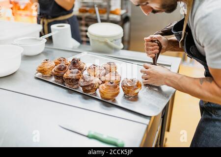 Bäcker dekorieren Zimtrollen an der Küchentheke Stockfoto