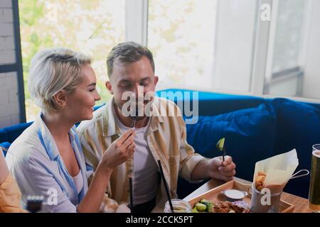 Junge kaukasische Paar haben romantische Zeit im Café, schöne Dame behandelt ihren Freund mit Essen Stockfoto