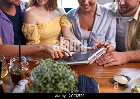 Freizeit, Leute und Urlaub Konzept. Gruppe von Freunden lesen Menü im Restaurant, wählen und gehen, um Ordnung zu machen Stockfoto