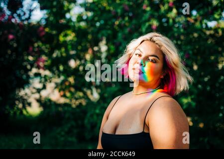 Plus Größe Frau mit Regenbogenlicht fallen auf ihr Gesicht Im Park Stockfoto