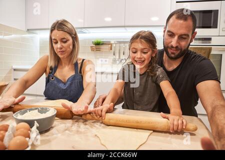 Glückliche Familie Kneten Pizzateig mit Rollstiften auf dem Tisch In der Küche Stockfoto