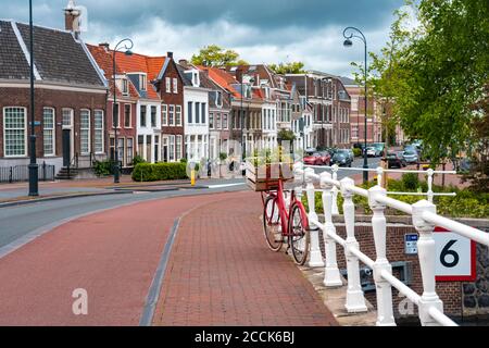 Niederlande, Nordholland, Haarlem, Fahrrad geparkt entlang Geländer der Kanalbrücke mit Häusern entlang Hooimarkt Straße im Hintergrund Stockfoto