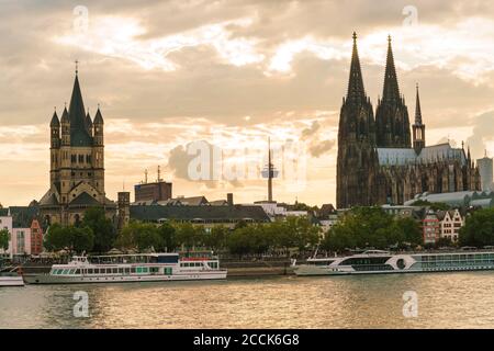 Deutschland, Nordrhein-Westfalen, Köln, Tourboote vor der Großen Martin Kirche und dem Kölner Dom in der Abenddämmerung Stockfoto