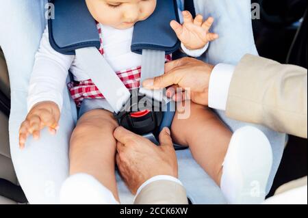 Vater Befestigung Baby Junge sitzen auf Kindersitz in einem Auto Stockfoto