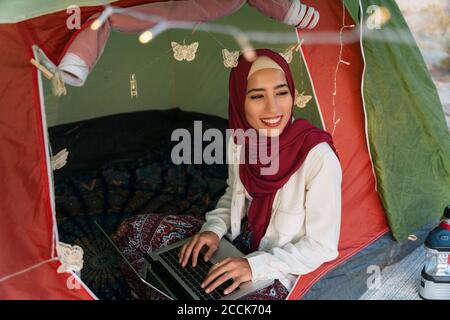 Junge Frau trägt Hijab mit Laptop in einem Zelt Stockfoto