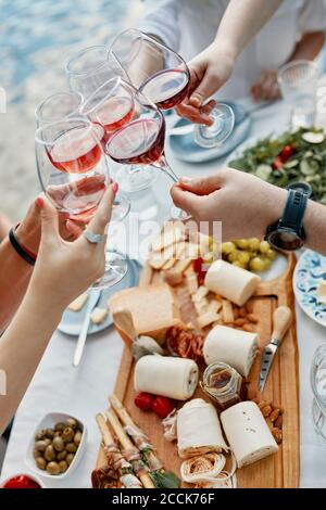 Freunde, die an einem See zu Abend essen, klirren Weingläser Stockfoto