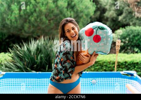 Fröhliche junge Frau hält Eis Spielzeug mit aufblasbaren Schwimmen Im Hintergrund Stockfoto