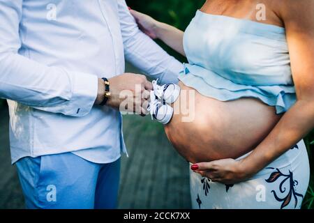 Mann berührt Bauch der schwangeren Frau mit Baby Booties Stockfoto