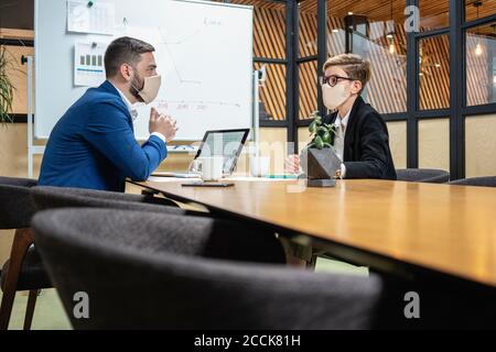 Profis, die Strategie planen, während sie am Schreibtisch im Konferenzraum sitzen Während der COVID-19-Epidemie Stockfoto