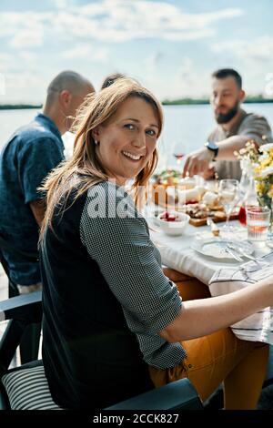 Portrait einer lächelnden Frau, die mit Freunden zu Abend gegessen hat Am See Stockfoto