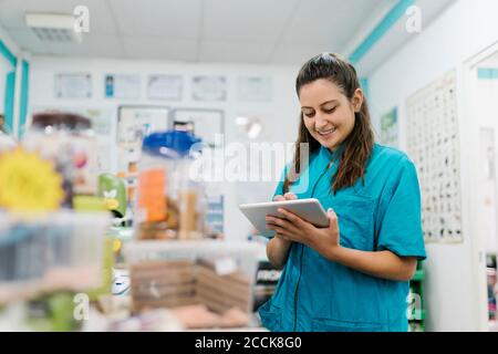 Lächelnde Pistenerin mit digitalem Tablet, während sie im Haustier steht Salon Stockfoto