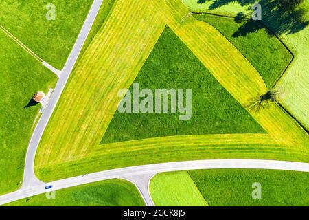 Deutschland, Bayern, Hopferau, Drohnenansicht der Kapelle St. Antonius und dreieckiges Feld im Frühjahr Stockfoto