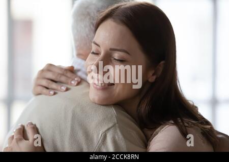 Liebevolle junge Frau umarmt alten pensionierten Papa drinnen. Stockfoto