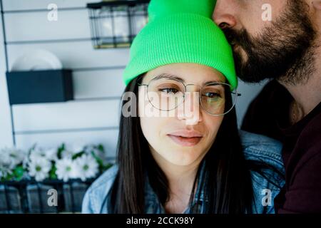 Nachdenkliche Frau, die zu Hause von einem Mann auf die Stirn geküsst wird Stockfoto