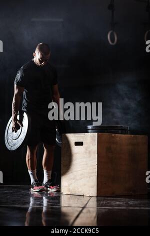 Muskulöser Sportler, der sich auf das Gewichtheben vorbereitet. CrossFit Trainer im Fitnessstudio. Stockfoto