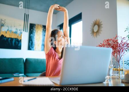 Müde Freiberuflerin Stretching Arme während im Home Office sitzen Stockfoto