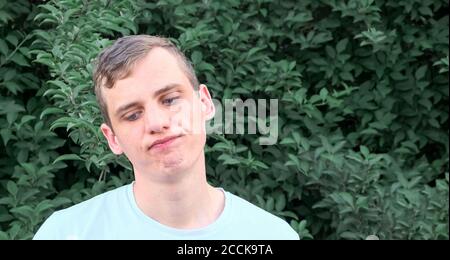 Porträt eines jungen unzufrieden Mann mit blauen Augen auf Ein Hintergrund von Grün Stockfoto