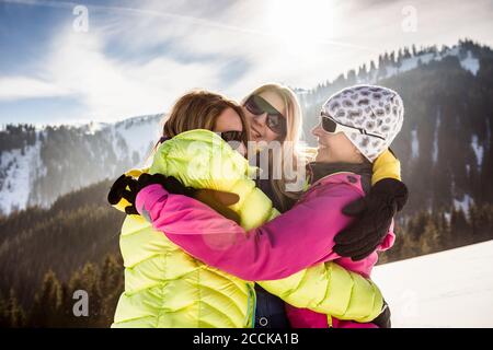 Drei glückliche Frauen umarmen sich in der Winterlandschaft, Achenkirch, Österreich Stockfoto