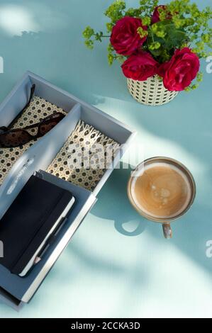 Kaffee, rote Rosen und handgefertigter Tischorganisator mit Sonnenbrille und Notizbuch Stockfoto