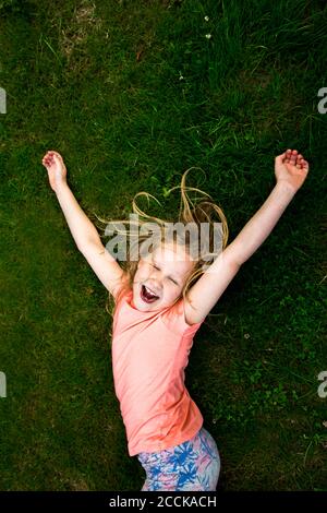Fröhliches Mädchen liegt auf Gras mit geschlossenen Augen Stockfoto