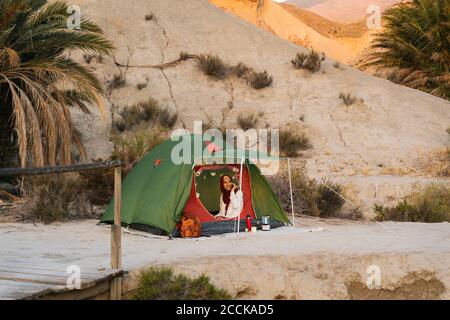 Lächelnde junge Touristenfrau, die Hijab in einem Zelt trägt Stockfoto