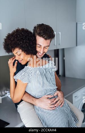 Romantische multi-ethnischen Paar umarmt in der Küche des Penthouse Stockfoto