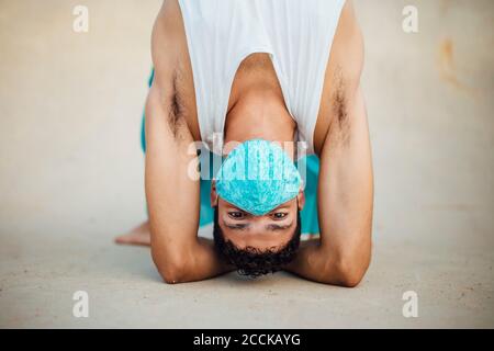 Junger Mann mit Maske üben rhythmische Gymnastik auf Sportrampe Stockfoto