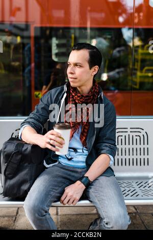 Mann in Casuals mit Kaffee, während auf den Bus warten Station Stockfoto